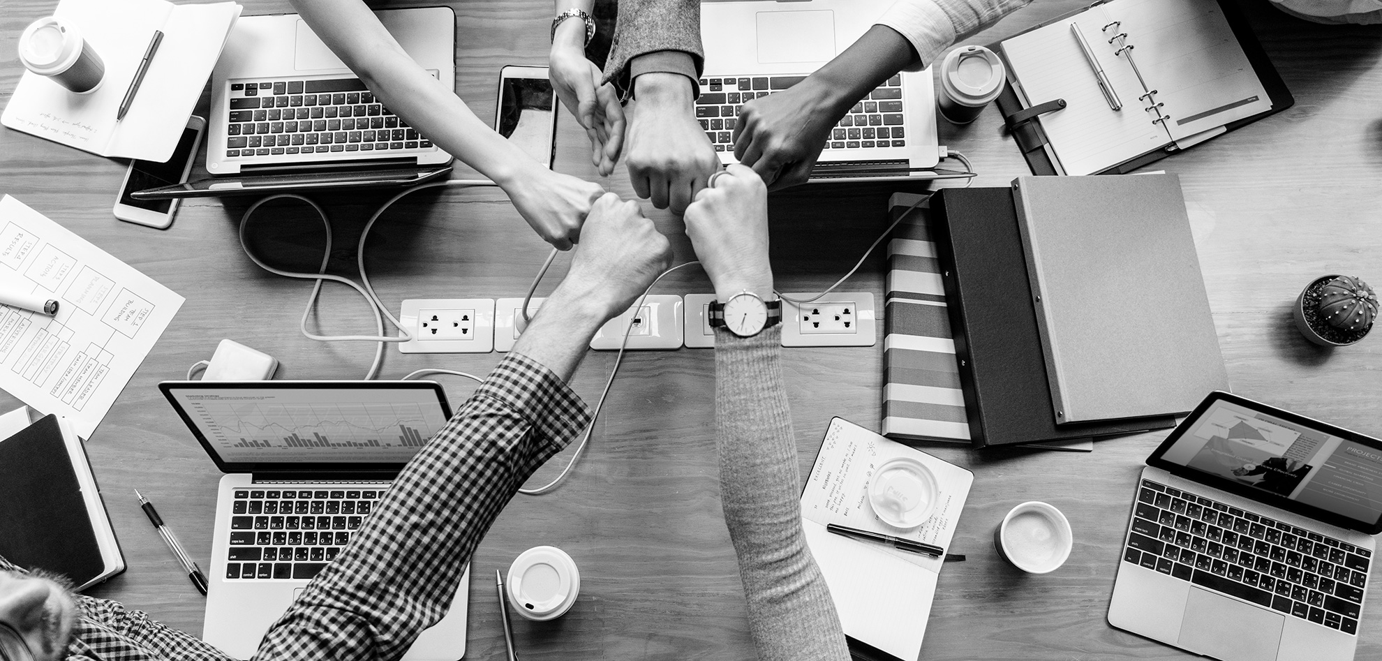 Team members joining hands during a collaborative project meeting